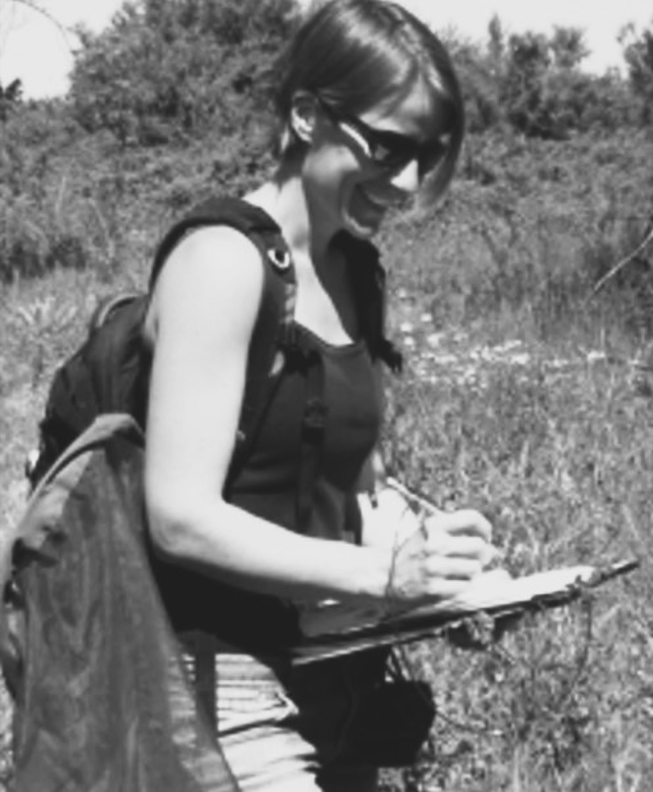 Julie Dalet en relevé de terrain, planchette à la main, sac à dos et filet d'inventaire